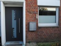 Kunststoff-Haustür dunkelgrau mit länglichem Milchglas-Einsatz mittig, in Neuss